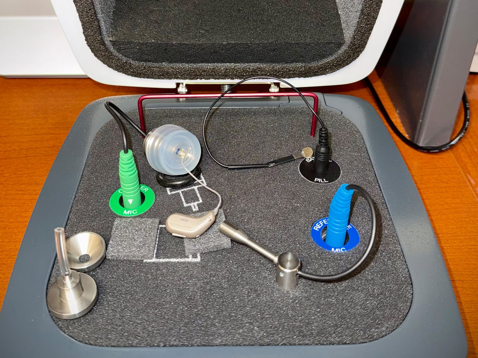 A hearing aid connected to the coupler microphone inside the open hearing aid test box